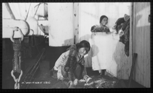 Image of Two Inuit women aboard. One kneels by furs on deck